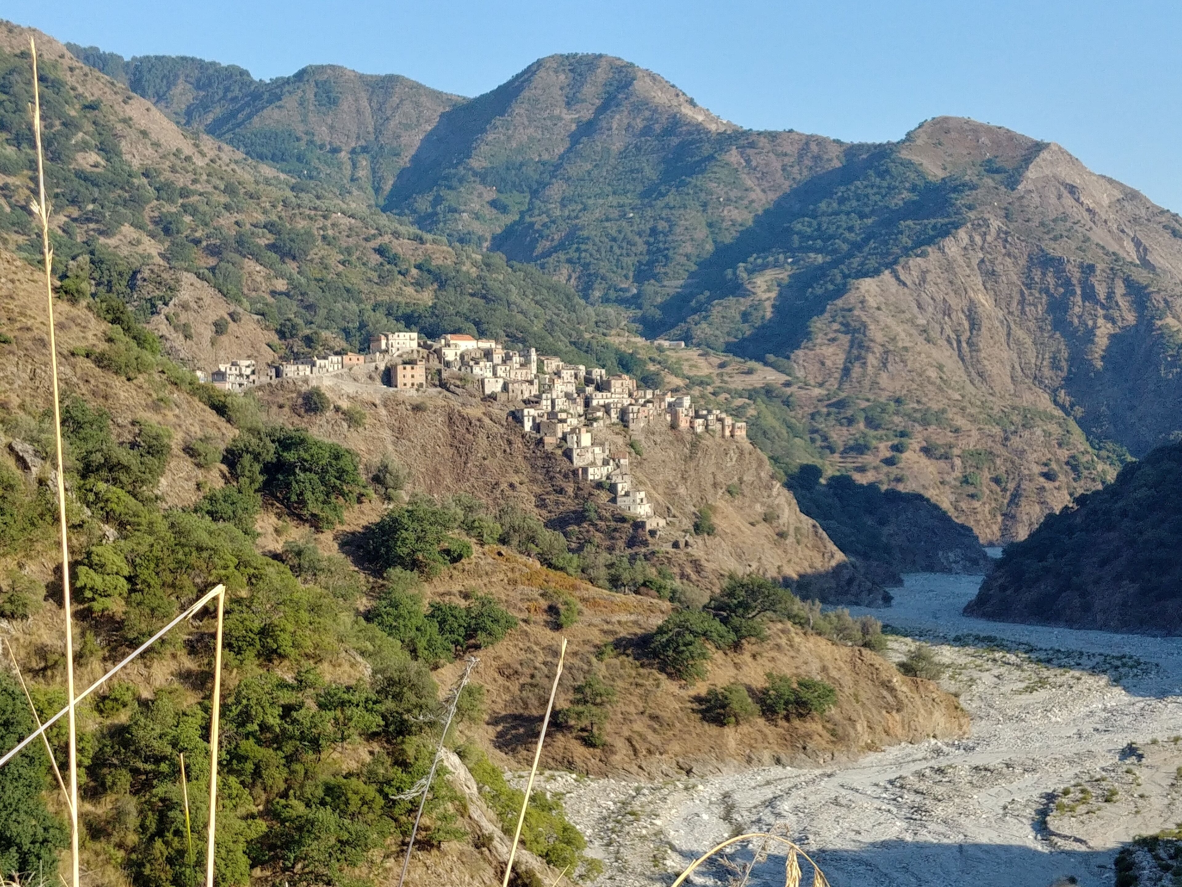 Un village de montagne dont les bâtiments sont construits sur le flanc d’une colline, surplombant une rivière.