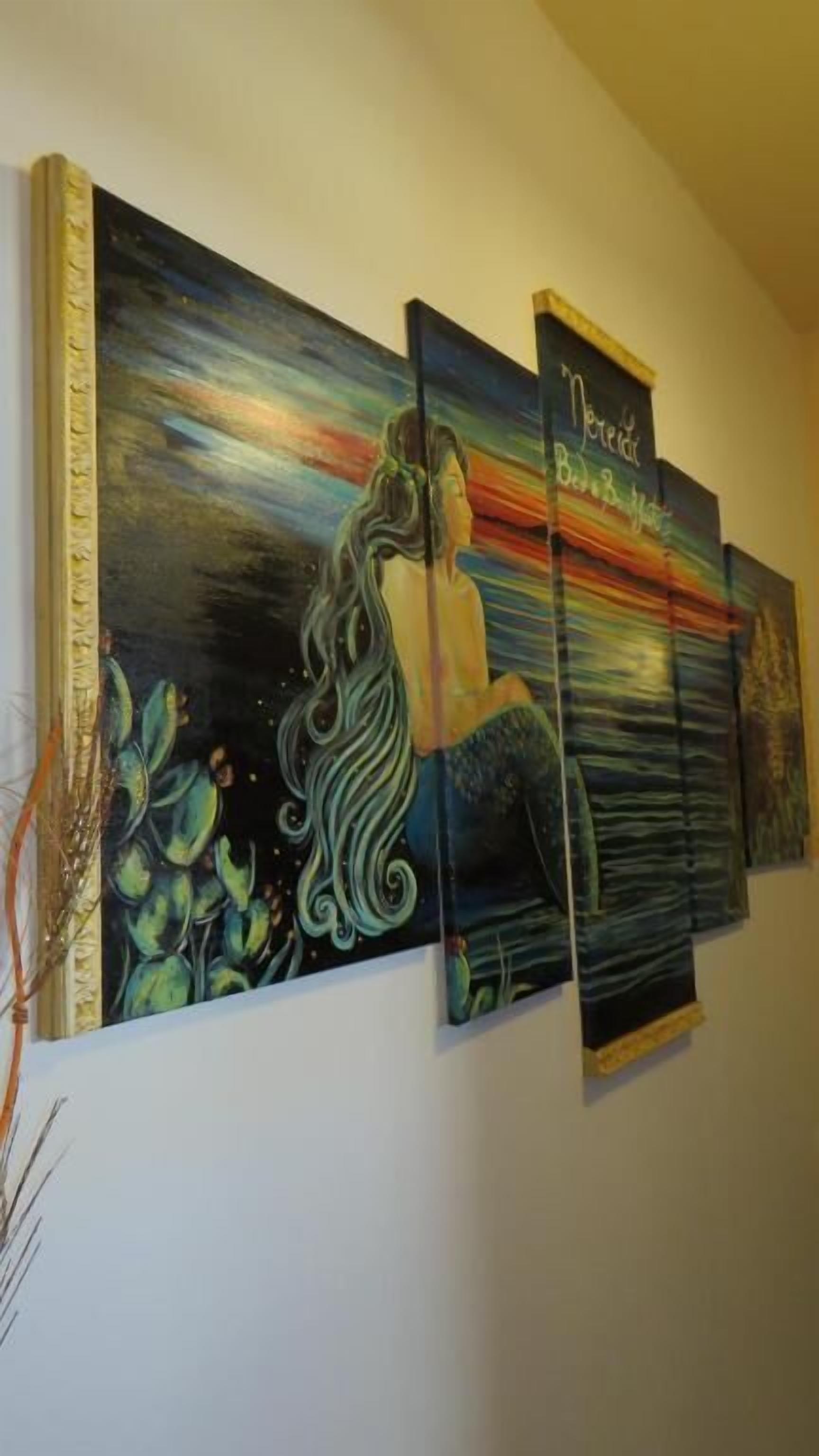 A wall with a large, abstract painting featuring a mermaid and a colorful sky.
