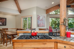 Una cocina con un hervidor rojo, armarios de madera y un comedor con sillas.