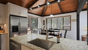 A modern kitchen with granite countertops, stainless steel appliances, and a wooden ceiling. - 3 Killdeer Lane Pet Friendly Home 3 Minutes Walk from SHARC by RedAwning (Bend)