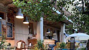 An outdoor seating area with various chairs and tables, a bar area in the background, and a wooden deck. - Hotel du Glacier (Fiesch)