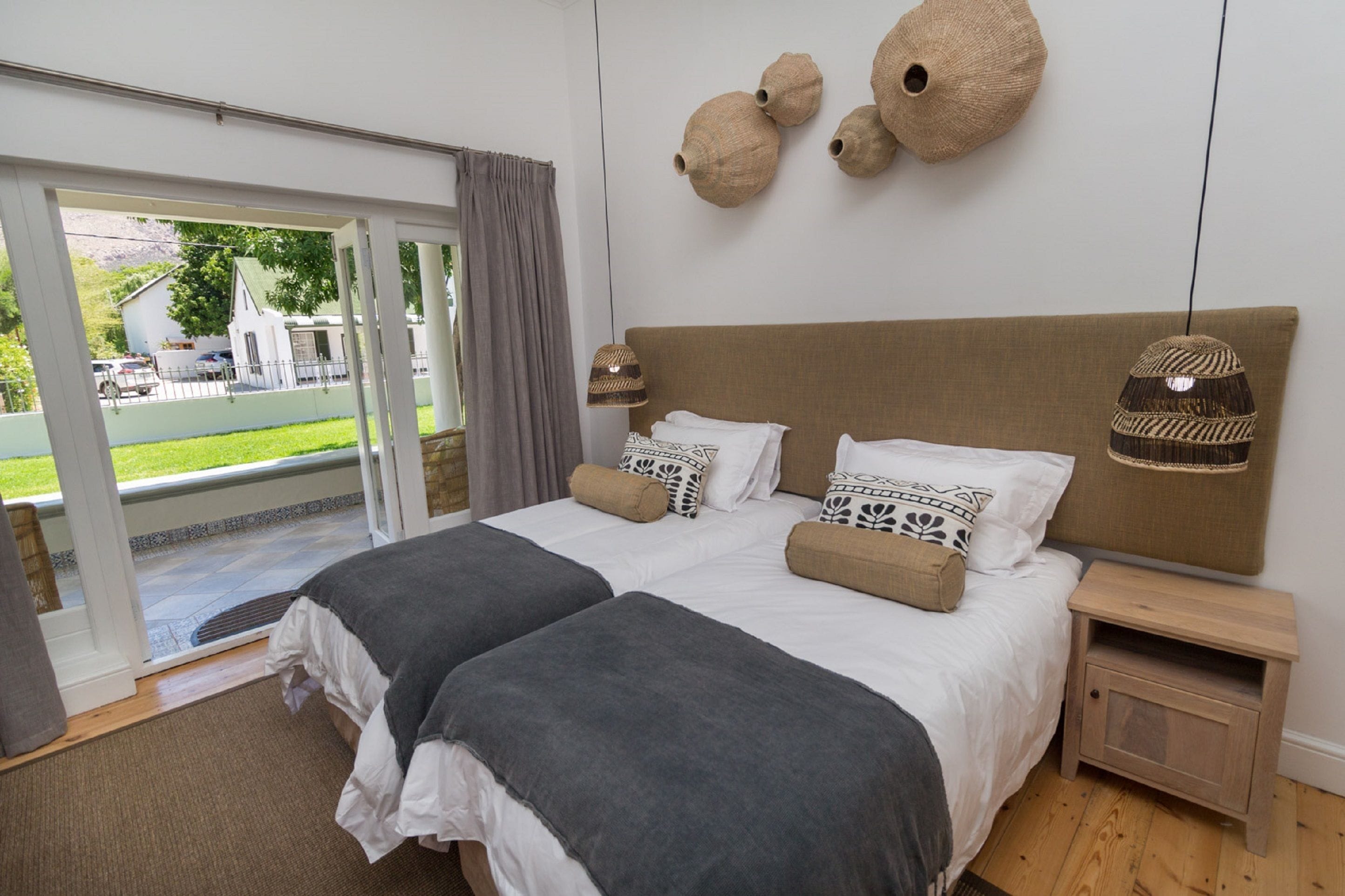 A bedroom with a large bed, two bedside tables, a nightstand, and a view of the outdoors.
