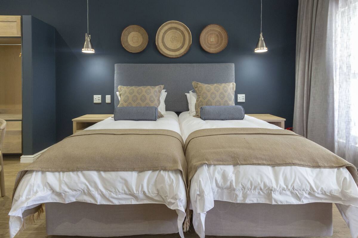 Una cama doble con dos almohadas, cabecero y tres platos decorativos en la pared.