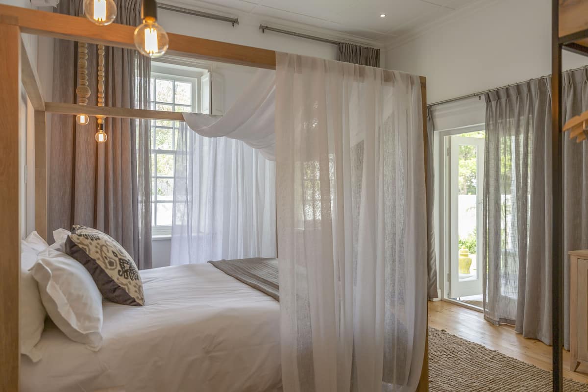 Un dormitorio con cama, cortinas ligeras y vistas al exterior.