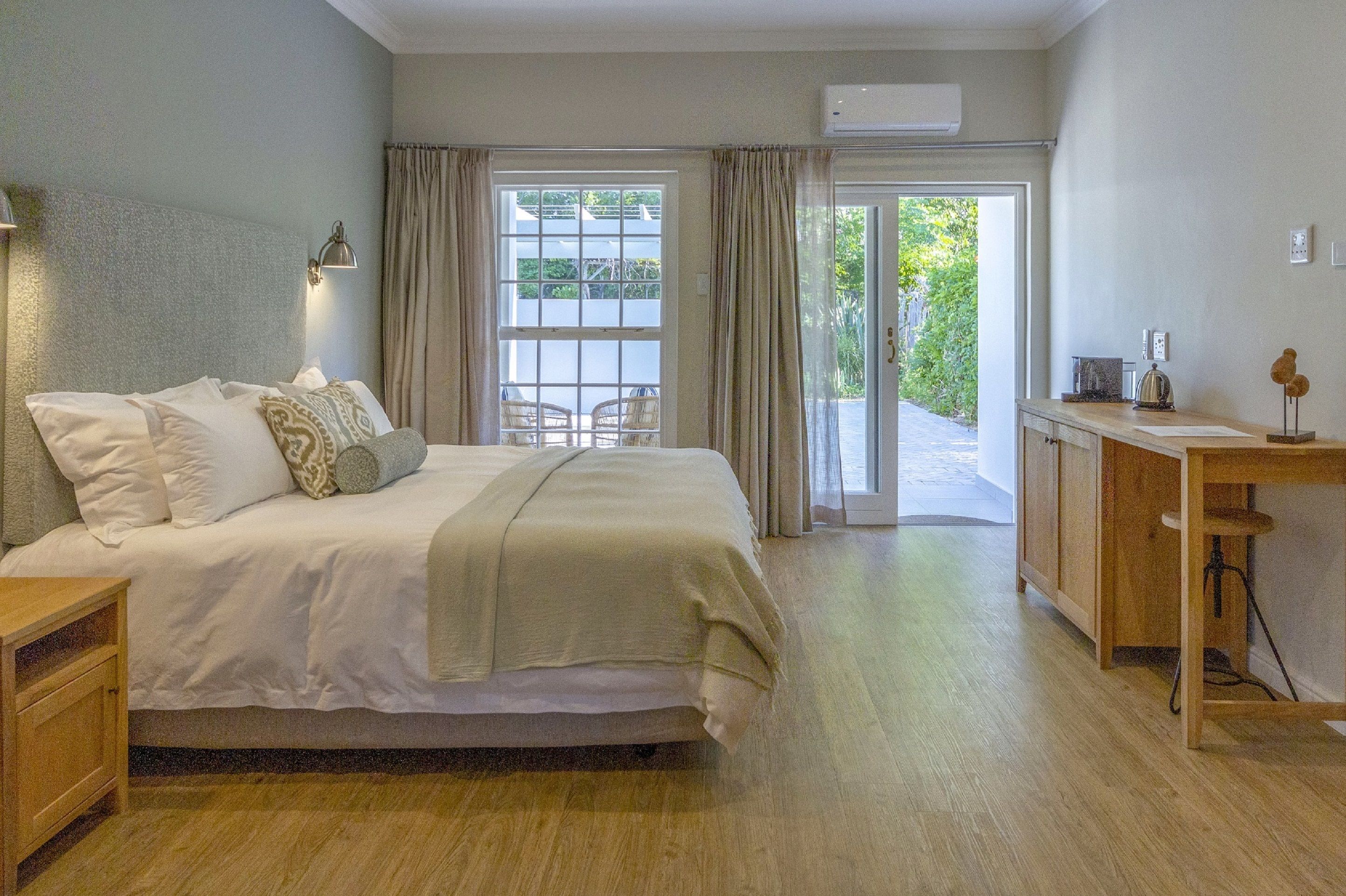 A bedroom with a bed, a desk, and a window with curtains.