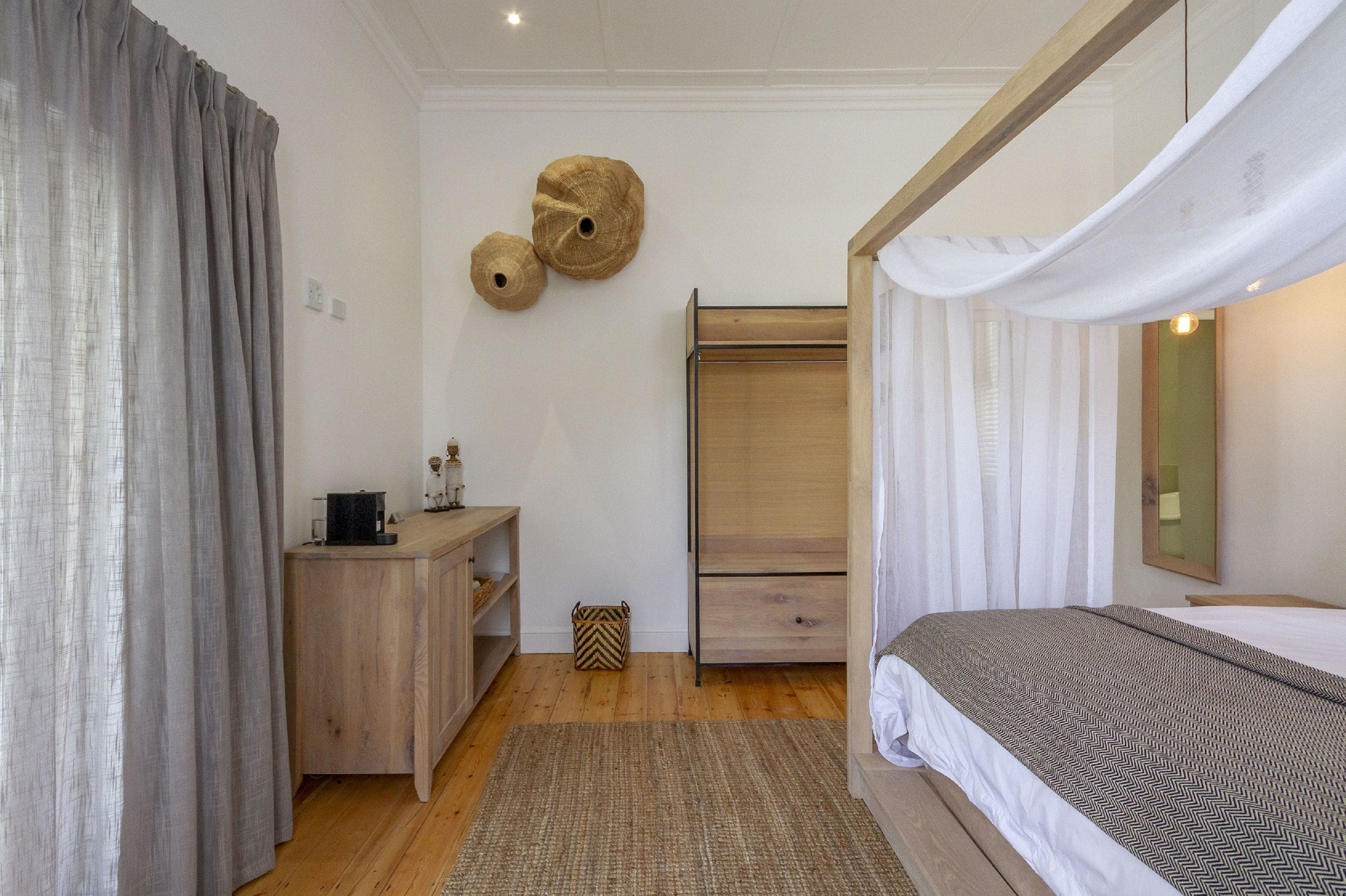 A bedroom with a bed, a wooden dresser, a wardrobe, and a mirror on the wall.