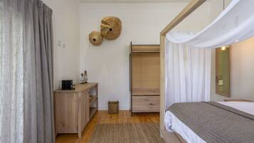 A bedroom with a bed, a wooden dresser, a wardrobe, and a mirror on the wall.