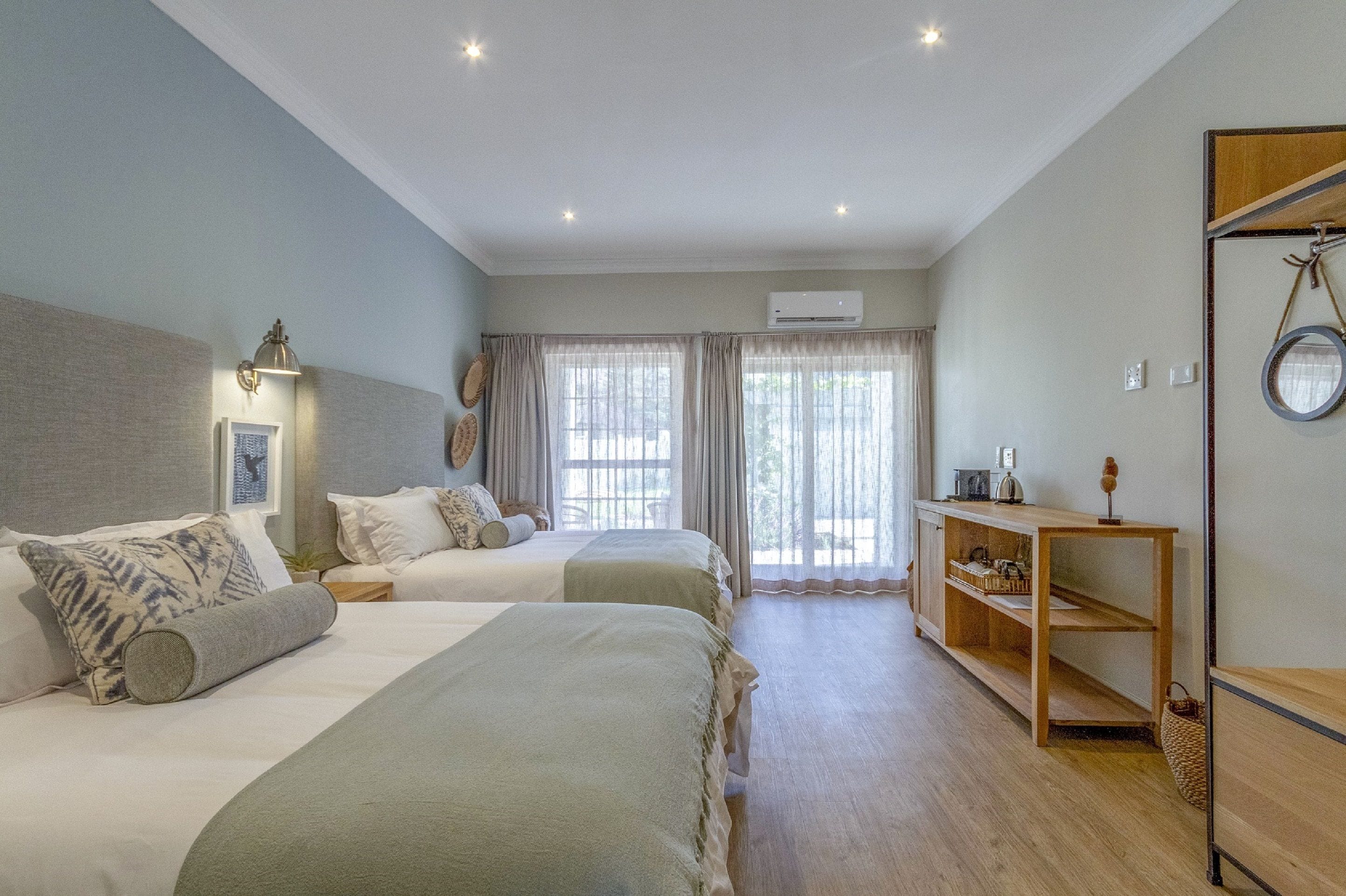A bedroom with two beds, a wooden shelf, and a window with curtains.