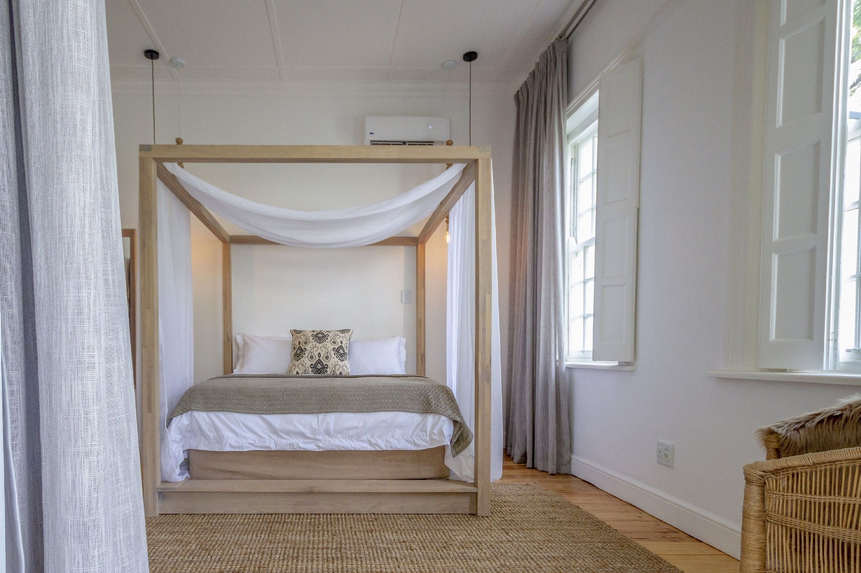 Une chambre à coucher avec un lit à baldaquin, un tapis tissé et une chaise en osier.
