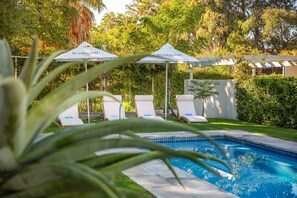 A pool area with lounge chairs and umbrellas, surrounded by greenery. - Monte Vista Boutique Hotel (Montagu)