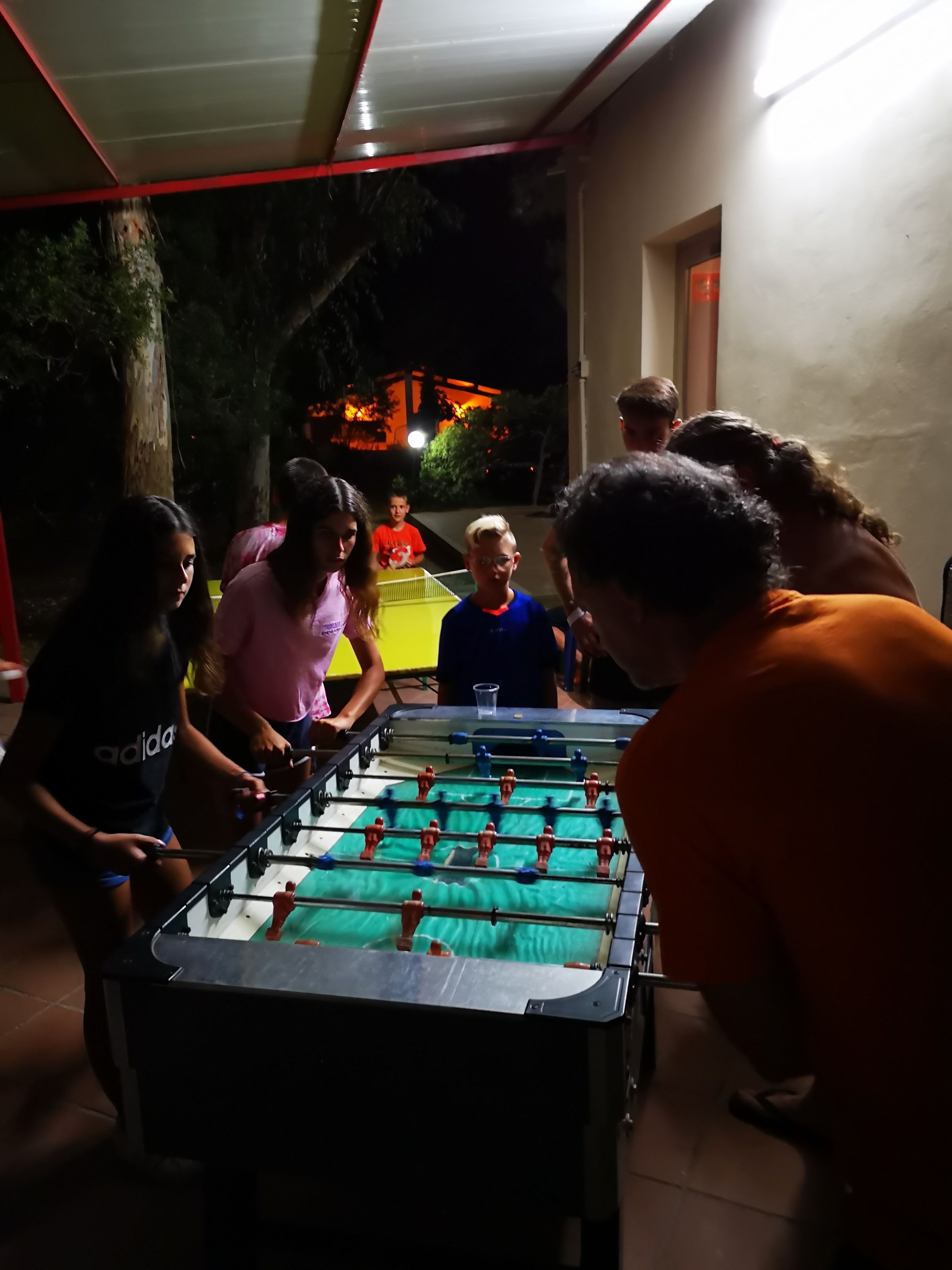 Un grupo de personas jugando al fútbol de mesa al aire libre de noche.