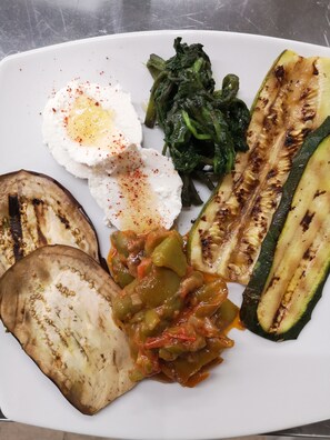 Un piatto con verdure alla griglia, un uovo in camicia e una fetta di pane.