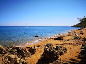 Una spiaggia con acqua cristallina, una riva sabbiosa e alcune persone.