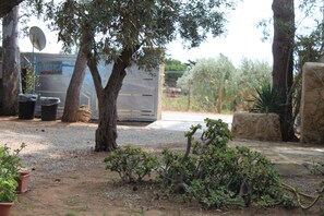 Un’area di parcheggio con un veicolo di grandi dimensioni, alberi e alcune piante in vaso.