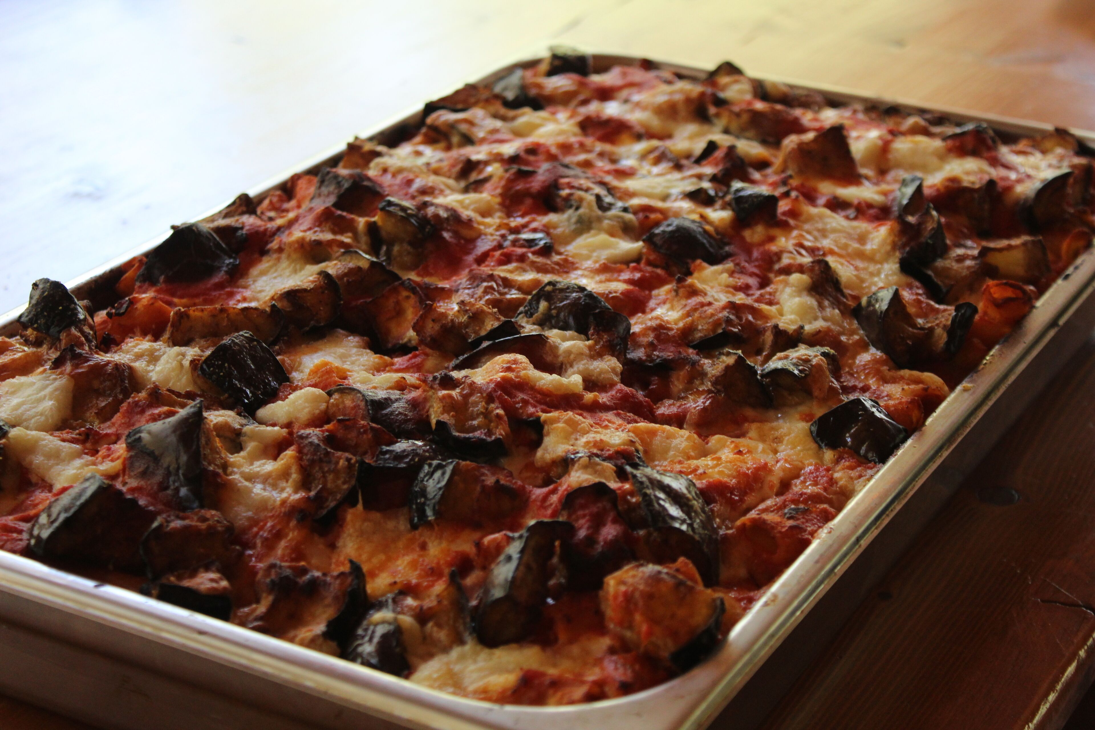 A rectangular baking dish filled with a baked dish, possibly lasagna, with visible layers of cheese and vegetables.