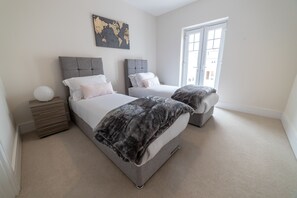 A bedroom with two beds, a world map on the wall, and a large window. - Reading Green Park Village Serviced Apt (Reading)
