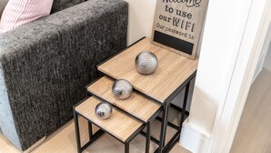 Una pequeña mesa de madera con tres adornos esféricos y un cartel de bienvenida en la pared.