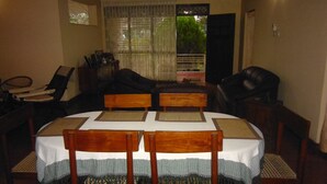 A dining area with a round table, four wooden chairs, and a white tablecloth.
