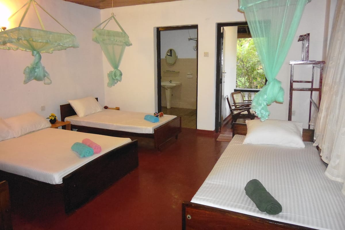 Une chambre avec deux lits, un plafond en bois, un lavabo et une vue sur la verdure.