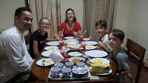 A family dining at a wooden table with various dishes, drinks, and cups.