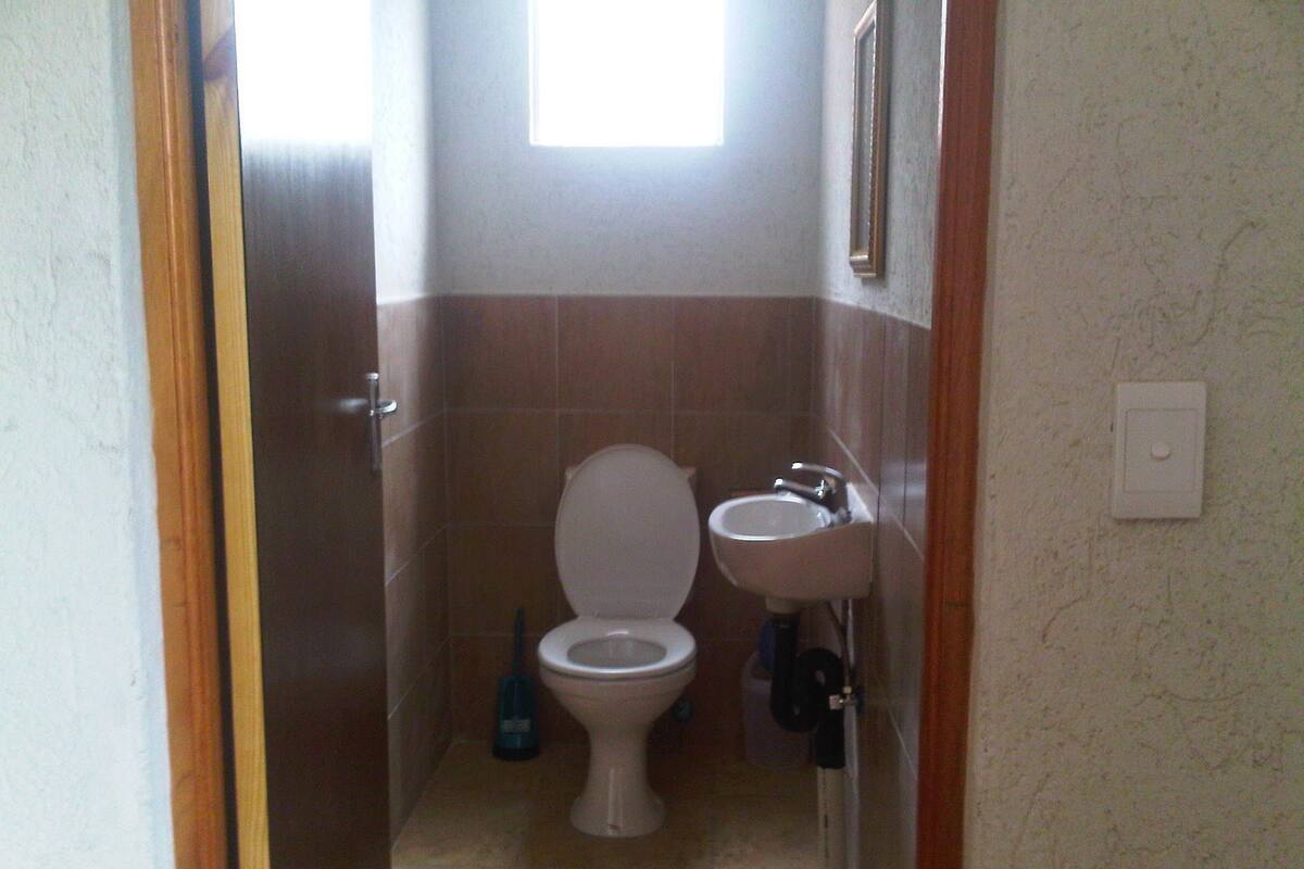 A small bathroom with a toilet, sink, and a window.