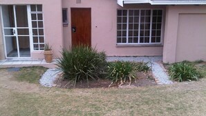 A single-story house with a pink exterior, a wooden door, and a window with a grid pattern. - Johannesburg Boarding Hostel (Randburg)