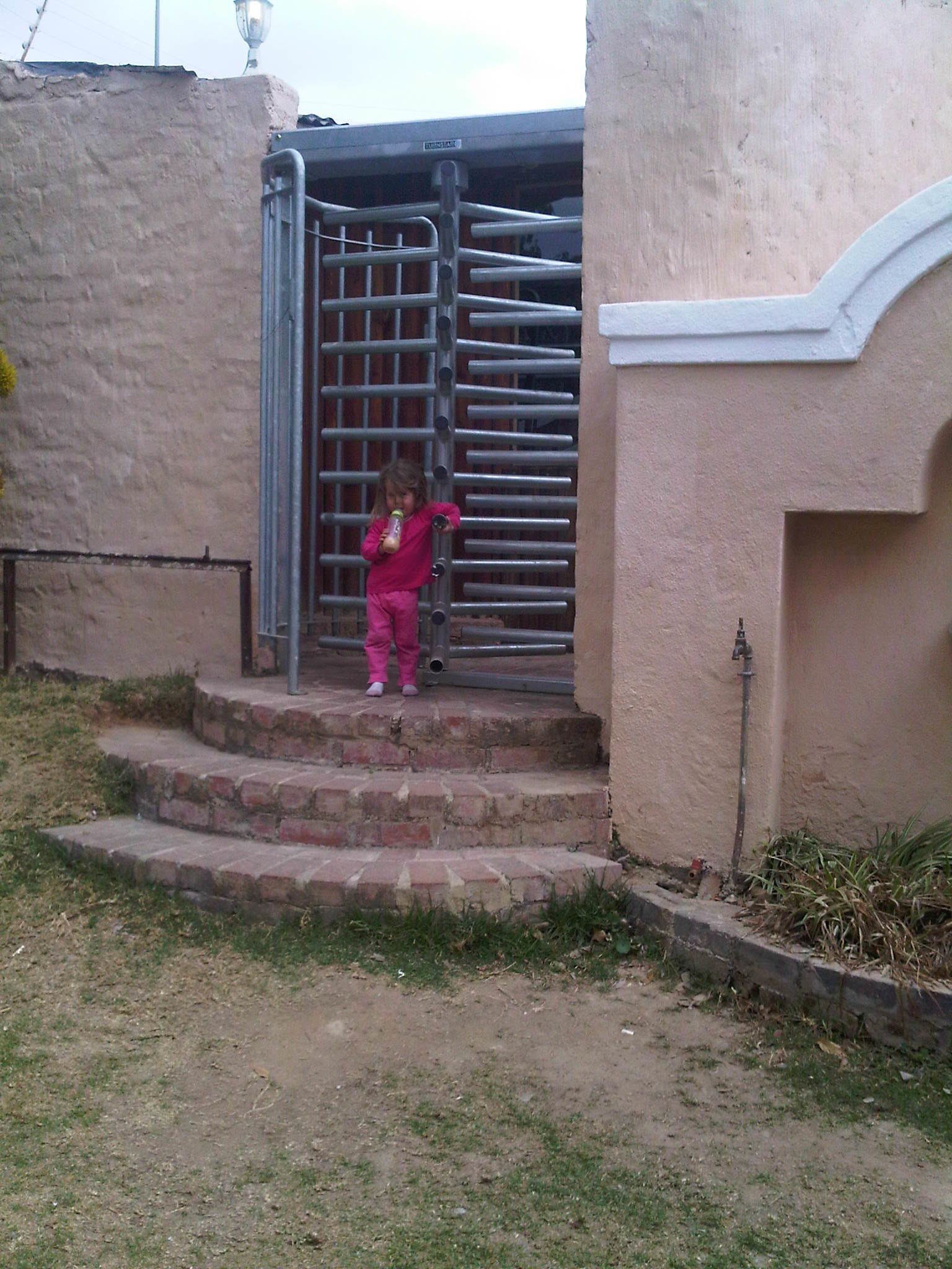 Un niño con ropa rosa de pie sobre una serie de escalones de piedra que conducen a una puerta de metal.