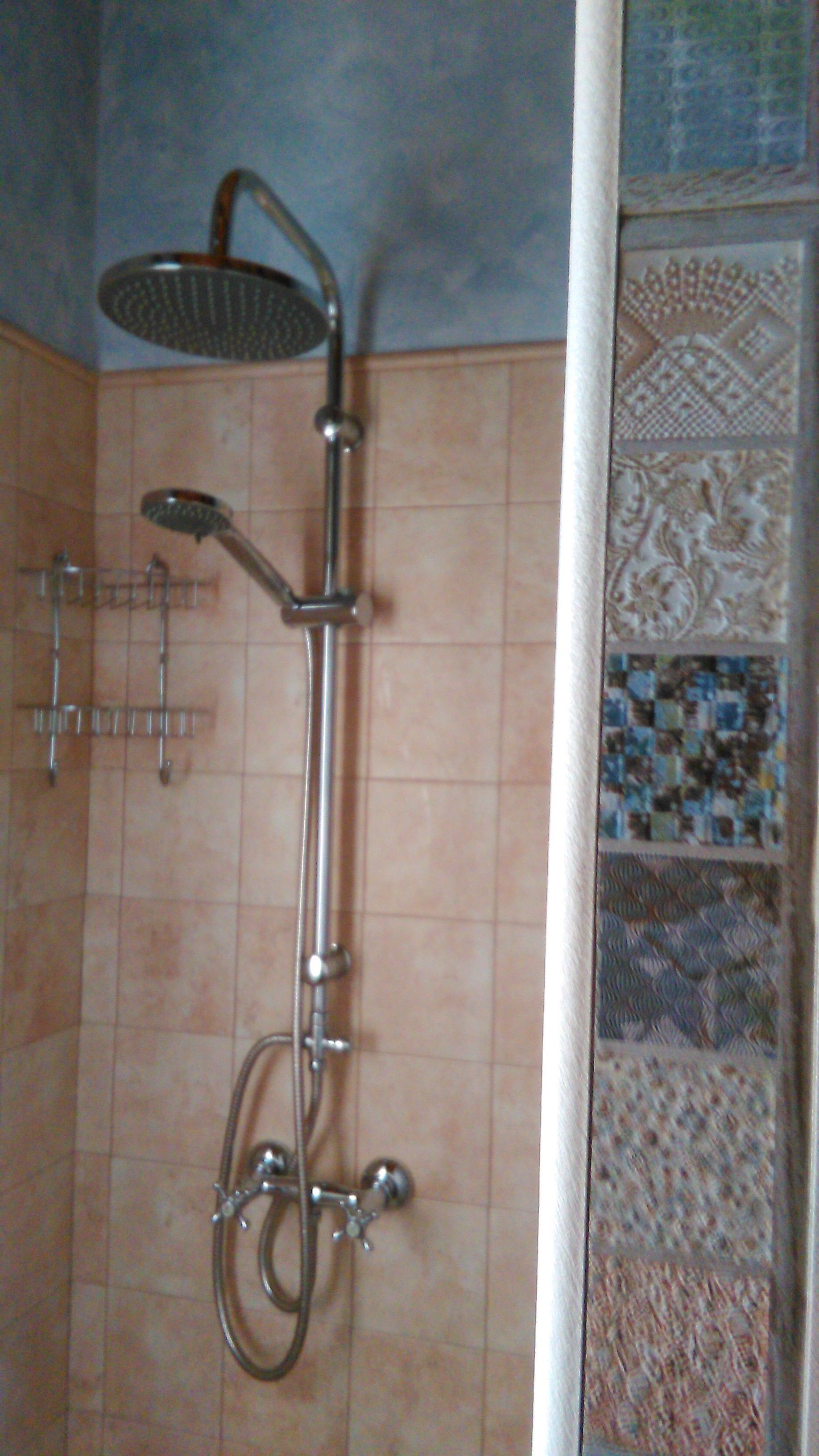 A shower with a handheld showerhead and a wall-mounted rain showerhead.