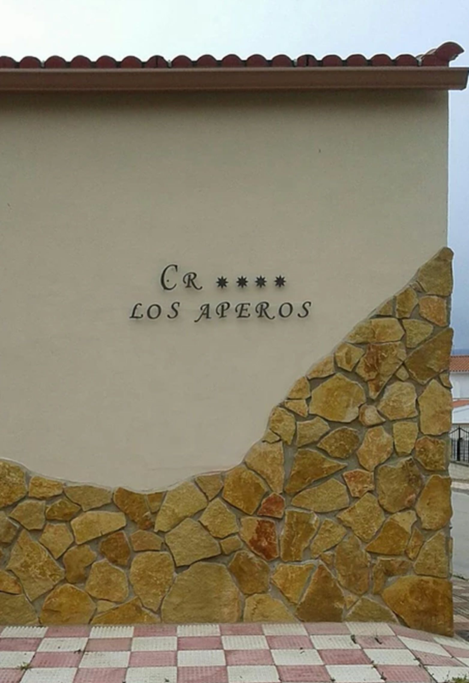 Fachada de un edificio con pared de piedra y tejado de tejas.
