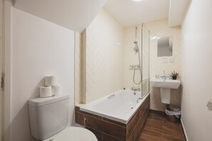 Une salle de bain moderne équipée de toilettes, d’une baignoire, d’une douche et d’un lavabo.