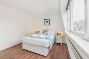 Une chambre à coucher avec un lit, des tables de chevet, une fenêtre et une vue sur la ville.