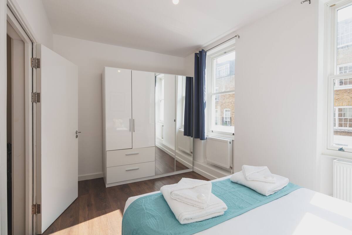 A bedroom with a bed, a wardrobe, and a window with curtains.