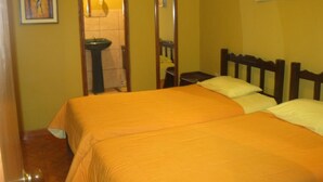 Una habitación con cama, mesita de noche, espejo y ventana.