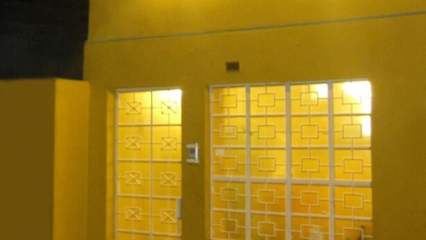 Un edificio con un cartel que dice "POSADA GINO" y dos ventanas iluminadas.
