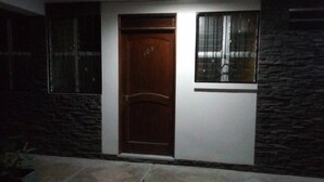 Un edificio con puerta de madera, ventana con barrotes de metal y pared de piedra.
