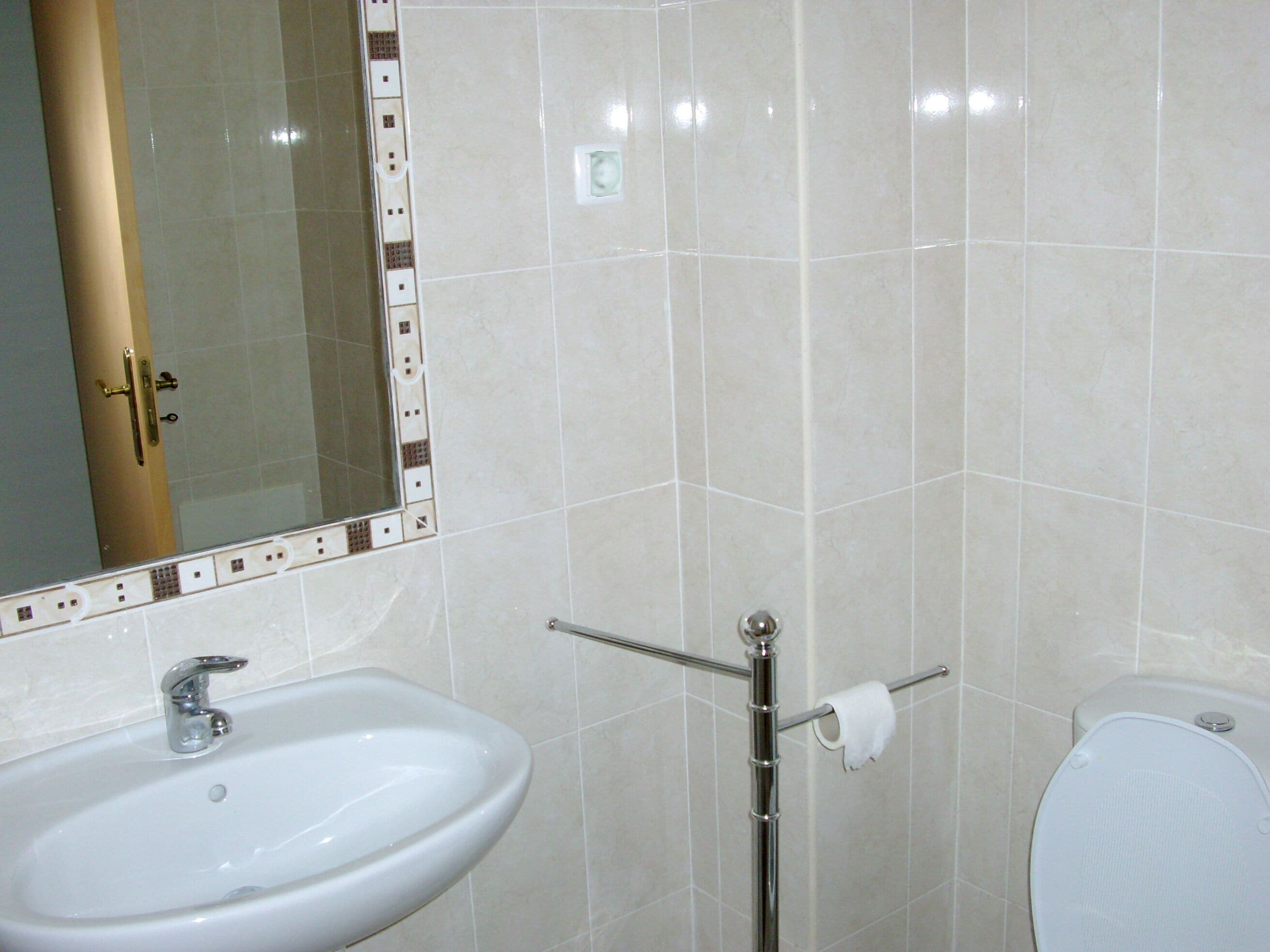 A bathroom with a sink, mirror, toilet, and towel rack.