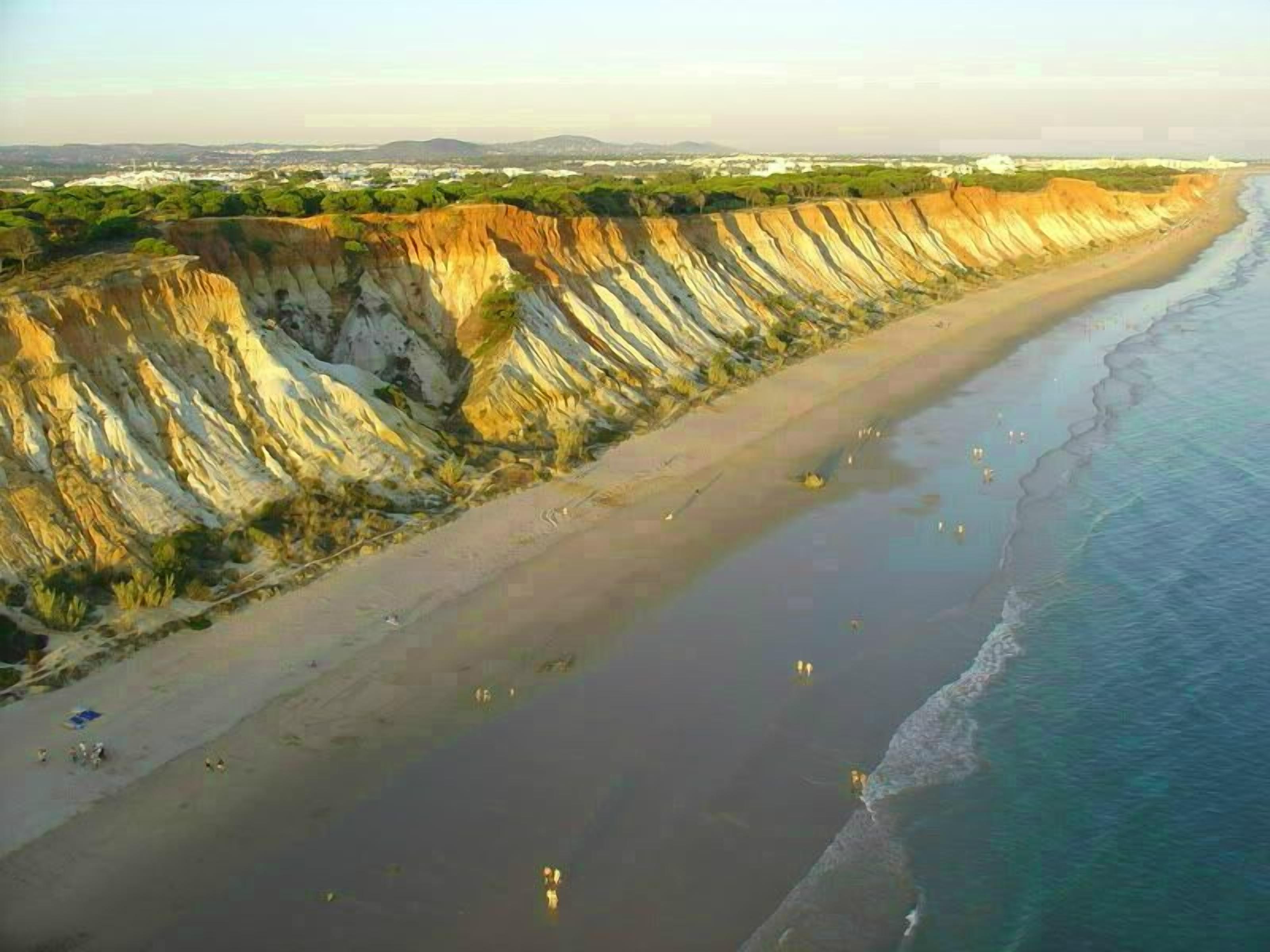 Paisatge costaner amb una àmplia platja de sorra i penya-segats.