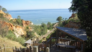 A wooden deck with a view of the ocean and rocky cliffs. - Deluxe Apartment with 2 Bedrooms B - 2 Br apts (Albufeira)