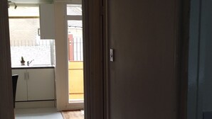 A hallway with a tiled floor leading to a kitchen area with cabinets and a window. - Stunning Apartment In London Tottenham (London)