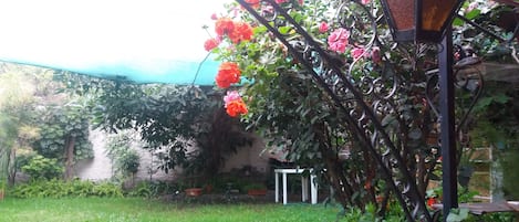 A garden with a metal lamp post, a blue canopy, and flowering plants.