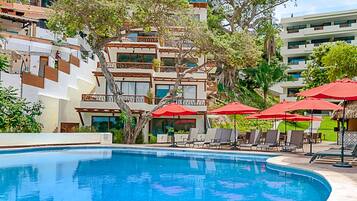 Alberca al aire libre, sombrillas en la alberca y camastros