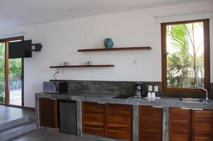 Una cocina moderna con lavavajillas integrado, cafetera y televisor de pantalla plana montado en la pared.