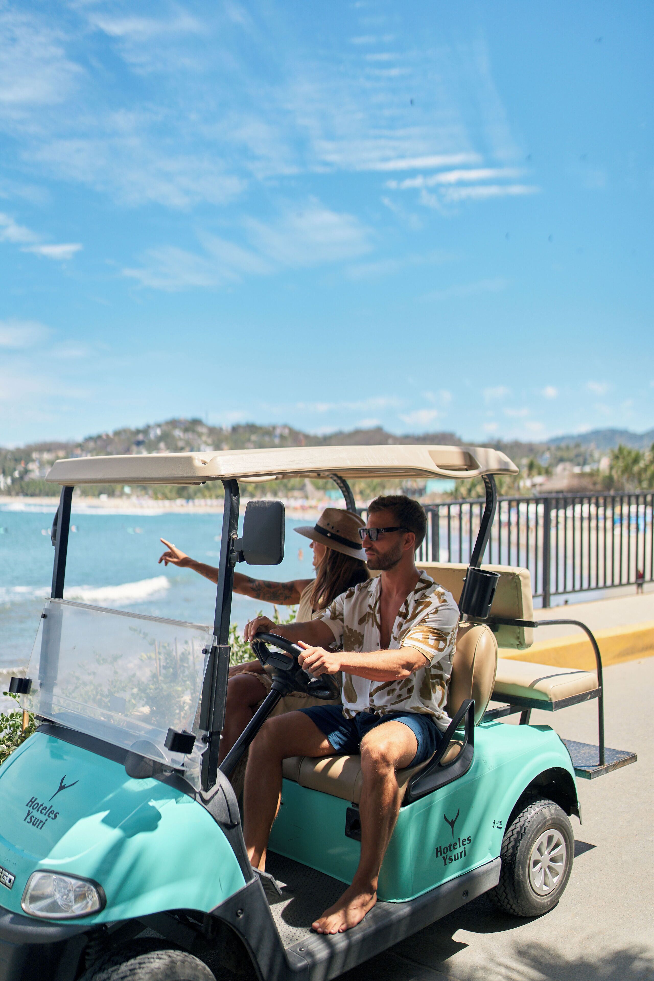 Un carrito de golf con vistas despejadas al océano y una playa al fondo.