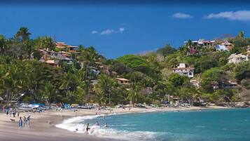 On the beach, black sand, sun-loungers, beach umbrellas