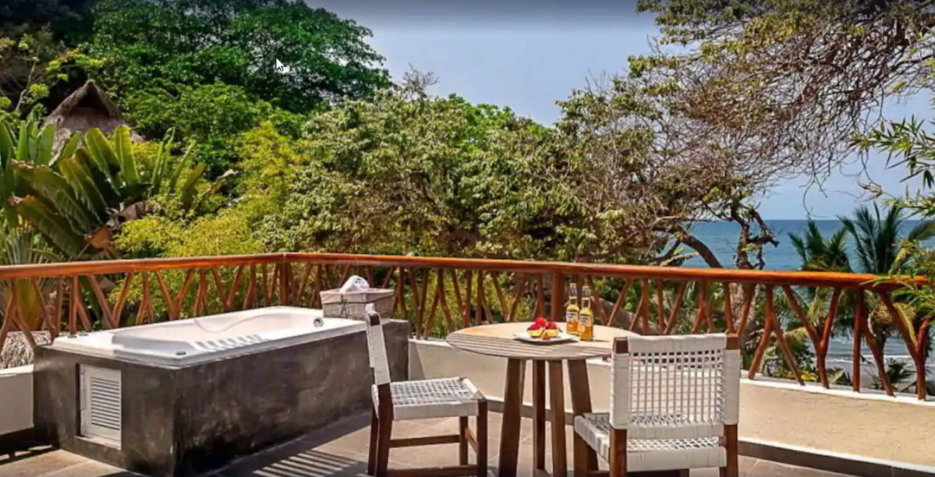 A balcony with a hot tub, seating, and a table with food.