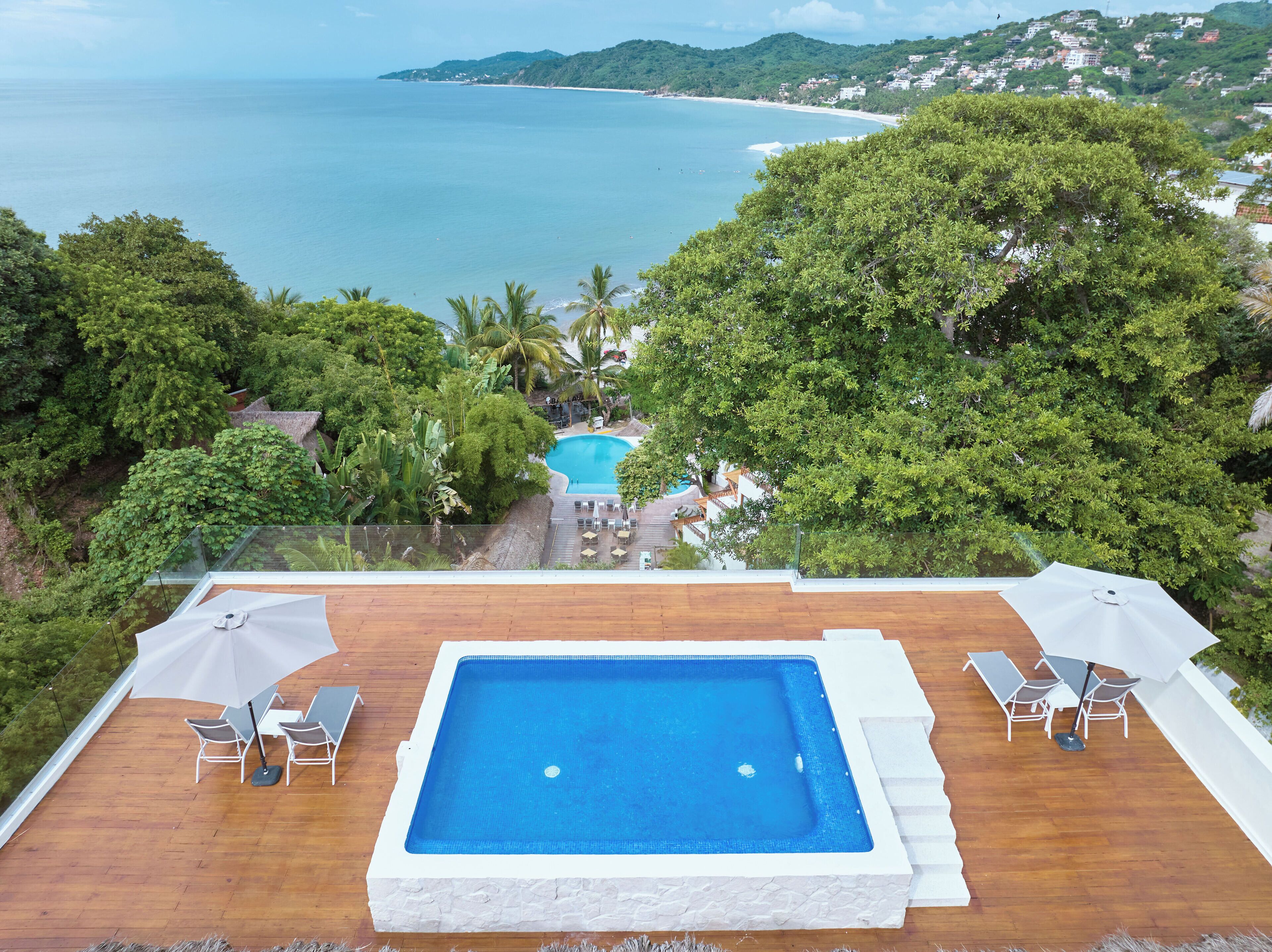 Una piscina en la azotea con vistas al mar y la vegetación circundante.