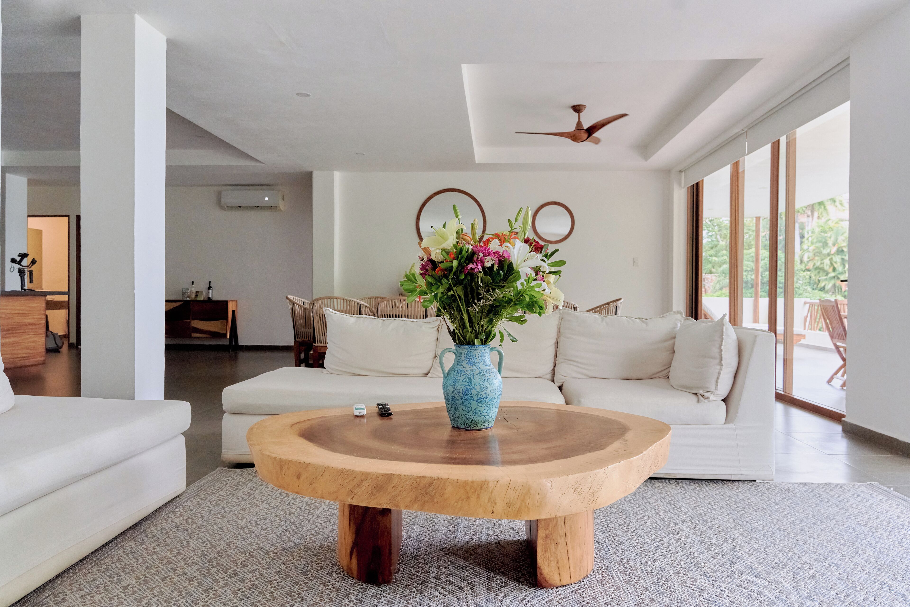 Una sala de estar moderna con una mesa de centro de madera, sofá blanco y un jarrón con flores.