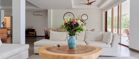 Una sala de estar moderna con una mesa de centro de madera, sofá blanco y un jarrón con flores.
