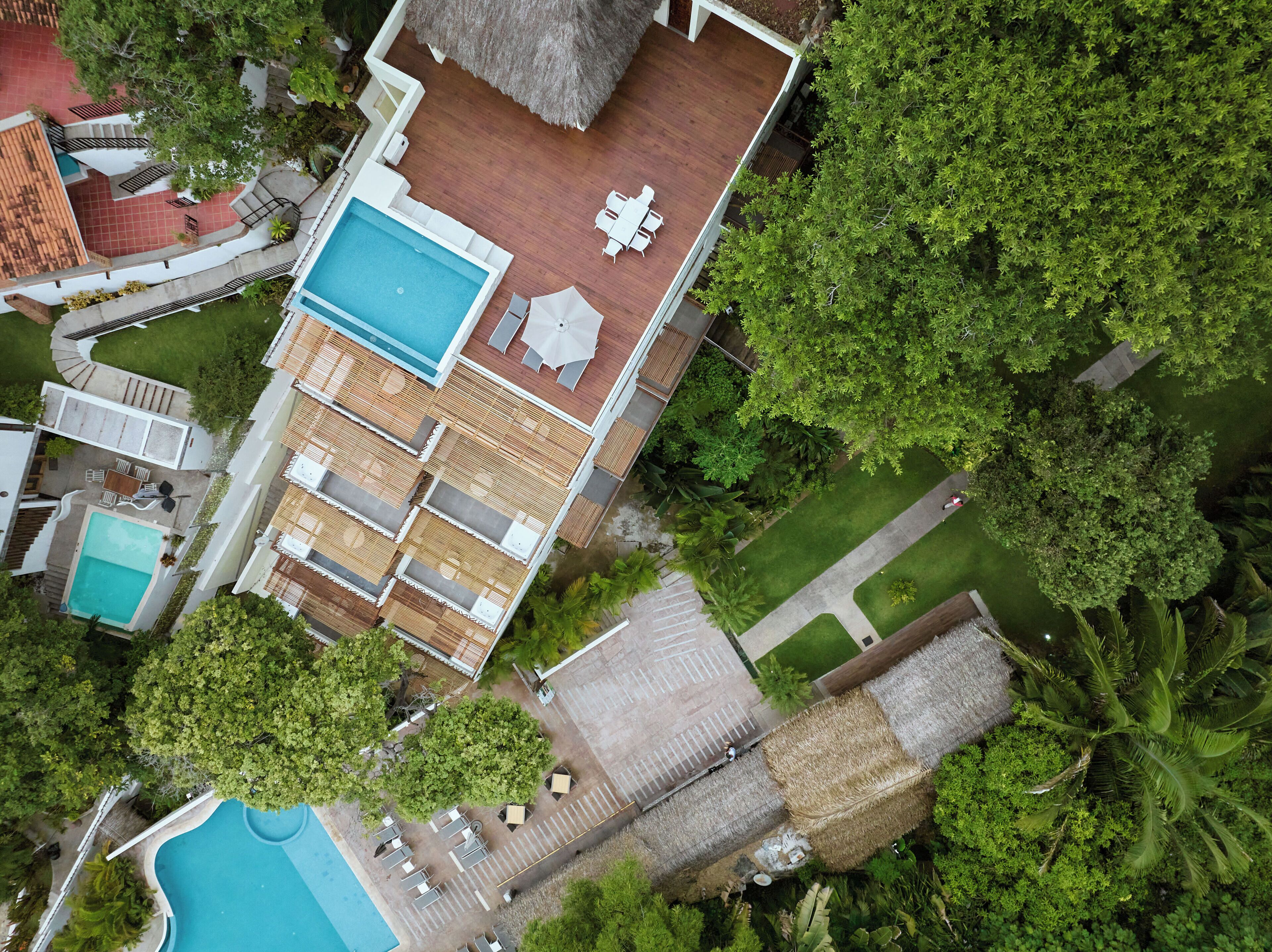 Vista aérea de un resort con múltiples piscinas, zonas de estar al aire libre y exuberante vegetación.