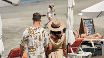 En la playa, playa de arena negra, camastros y sombrillas